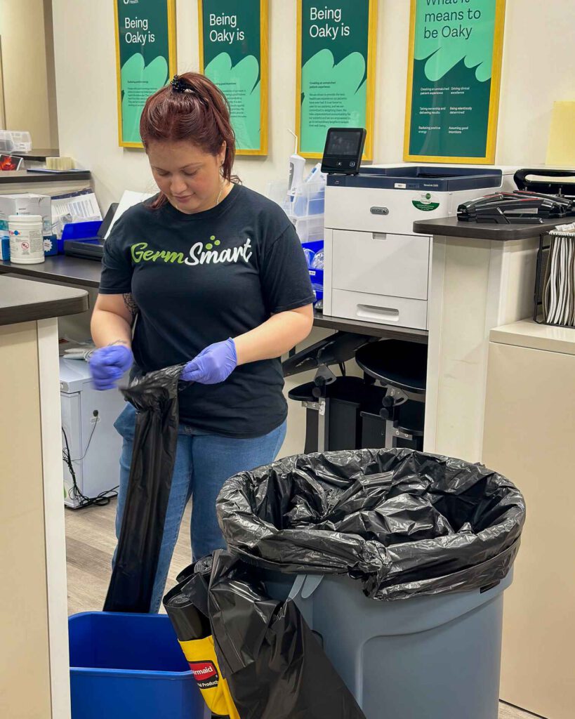 woman taking out trash inside an office space with desks