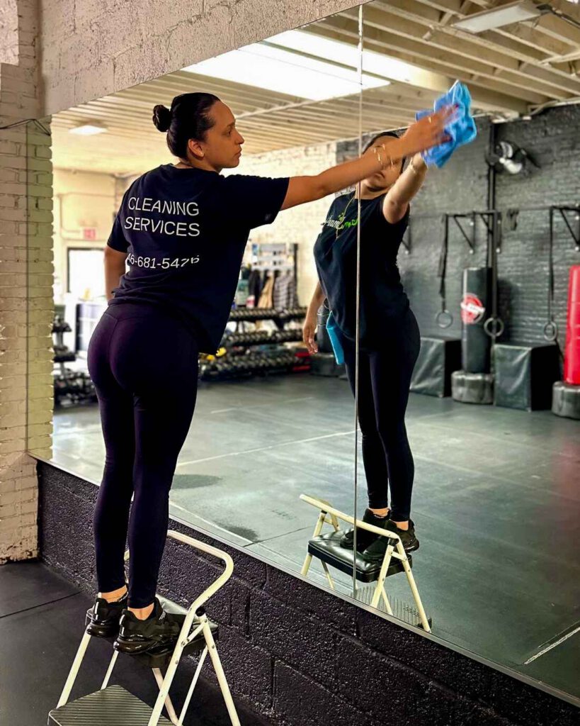 Woman wiping down a window inside of a gym