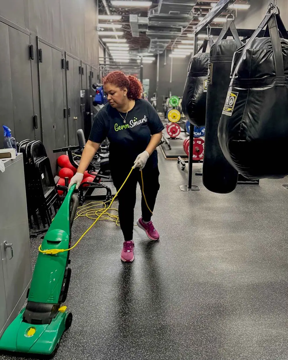 GermSmart cleaner vacuuming around equipment in a gym