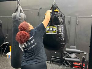 Cleaning Professional cleaning the top of a punching bag in a new york gym