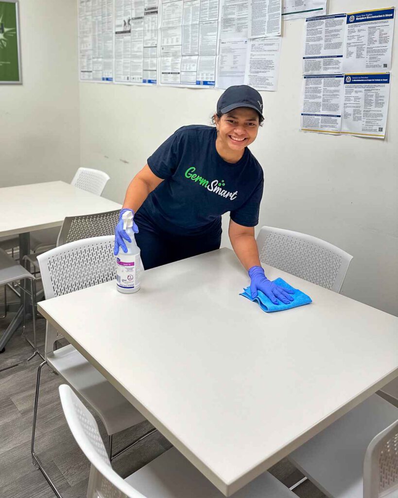 Cleaning employee disinfecting a table in an office.